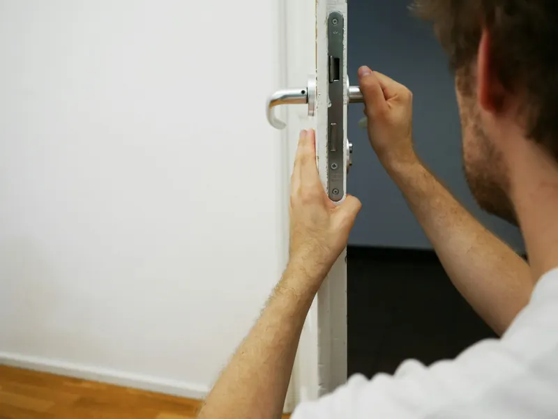 Serrurier ouvrant une porte d'entrée en tenant le battant et la poignée