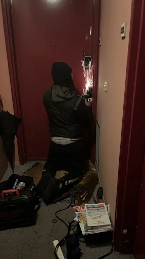 Serrurier agenouillé travaillant sur la serrure d'une porte d'entrée